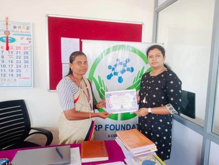 A facilitator presents a certificate at an SRP Foundation office as part of an education partnership.