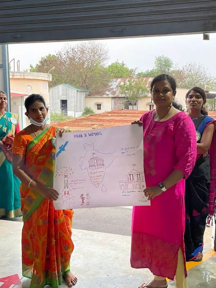 A facilitator presents a hand-drawn awareness chart to women during an SRP Foundation legal-literacy session.